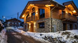une maison en bois éclairée dans la neige dans l'établissement Elegance Home, à Cortina dʼAmpezzo