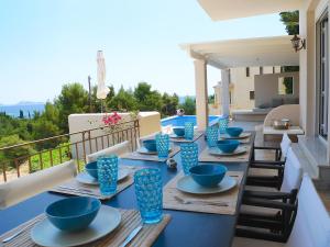 a table with blue bowls and plates on a balcony at Pentathlon Villa Collection - Porto Cheli Private Pool Getaways in Porto Heli