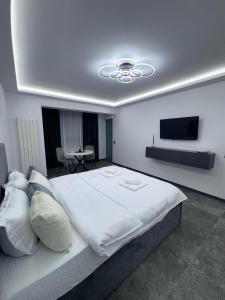 a bedroom with a large white bed and a flat screen tv at Grey Serenity in Brăila