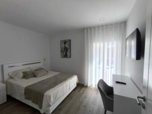 a white bedroom with a bed and a television at Casa de Campelo in Vila Nova de Cerveira