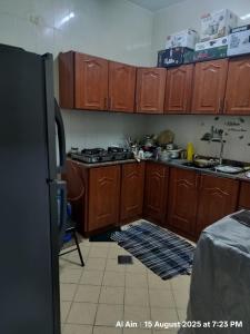 a kitchen with wooden cabinets and a refrigerator at Happy Homes in Al Ain