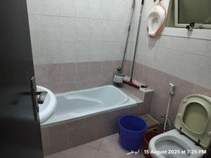 a bathroom with a tub and a toilet and a sink at Happy Homes in Al Ain