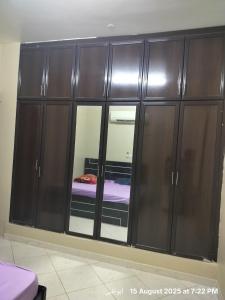 a large wooden cabinet with a bed in a room at Happy Homes in Al Ain