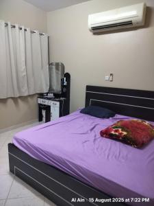 a bedroom with a bed with purple sheets and a fan at Happy Homes in Al Ain