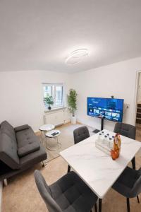 a living room with a table and chairs and a tv at Munich Premium Guesthouse in Munich