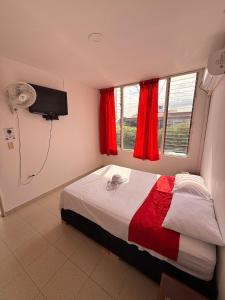 a bedroom with a bed and a fan and a window at Hotel Atalayas in Yopal