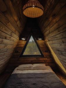 a bed in a wooden cabin with a window at Aframe Shepit in Sosnovka