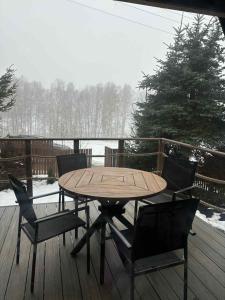 een houten tafel en stoelen op een terras in de sneeuw bij The Nest - Sauna and Hot Tub in Rynoltice +6 foto's