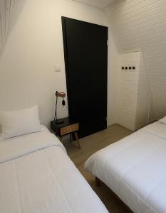 two beds in a room with a black door at The Nest - Sauna and Hot Tub in Rynoltice