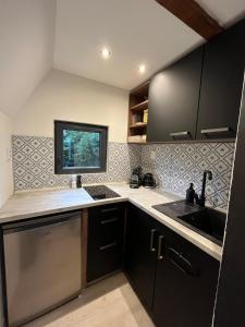 een keuken met zwarte kasten, een gootsteen en een raam bij The Nest - Sauna and Hot Tub in Rynoltice