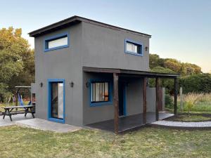 a gray house with blue windows and a picnic table at Casa Alfonsina in Chapadmalal +9 photos