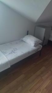 een slaapkamer met een bed met witte lakens en een houten vloer bij Alpha vision Smestaj in Belgrado