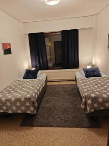 two beds sitting in a room with a window at Patomajat in Rovaniemi