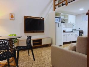 a living room with a tv and a table and a kitchen at Cataratas Loft Residence in Foz do Iguaçu