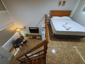 a bedroom with a large bed and a staircase at Cataratas Loft Residence in Foz do Iguaçu