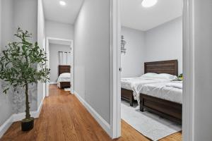 a white bedroom with a bed and a potted plant at 3 BR • Full Kitchen • Sleeps 8 in Jersey City +17 photos