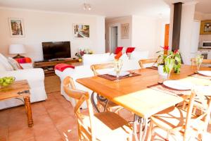 a living room with a wooden table and white chairs at Simonstown Penthouse in Simonʼs Town