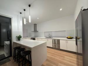 a white kitchen with a counter and stools in it at Seas the Day - Bay Stay in Tootgarook