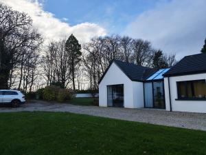 a white house with a car parked in the driveway at Woodville Apartment in Rathmullan