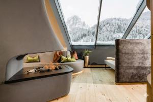 a living room with a fireplace and large windows at Hotel Touring Dolomites in Santa Cristina Gherdëina