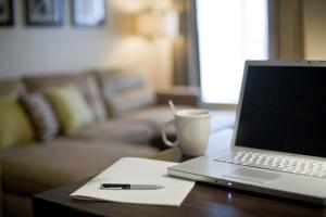 a laptop computer sitting on a table with a pen and a cup at Hyatt House Royal Oak / Birmingham in Royal Oak