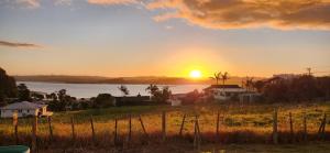 een zonsondergang boven een waterlichaam met een huis bij Country Harbourside Escape in Whakapirau