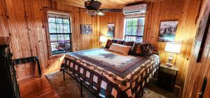 een slaapkamer met een bed met houten wanden en ramen bij Cliffside Cabin at Piney Falls - with Creek Access 