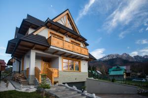 une maison avec un toit en gambrel dans l'établissement Domek za Strugiem - pokoje i apartamenty, à Zakopane