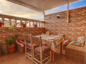 a patio with a table and chairs and a brick wall at Belle Maison Taghazout in Taghazout