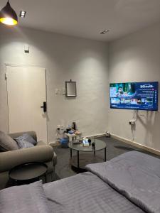 استديو بطابع هادي في الخبر: غرفة معيشة مع أريكة وتلفزيون على الحائط