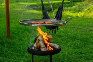 ein Grill mit Würstchen und einem Feuer in der Unterkunft Tiny Silent House River in Zblewo