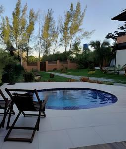 a patio with a chair and a swimming pool at Casa Rústica - Próx à Praia in Saquarema