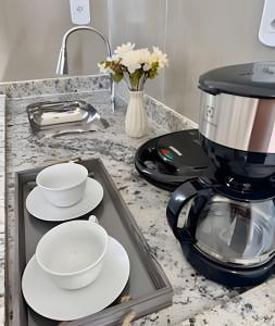 eine Kaffeemaschine auf einer Theke mit Tellern und Tassen in der Unterkunft Suíte aconchegante a 3 min da Praia do Pontal! (3) in Arraial do Cabo