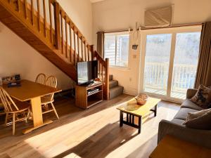 a living room with a couch and a table with a tv at Two Bedroom Loft Apartment Sleeps 8 with River Views near Loon Mountain in Lincoln