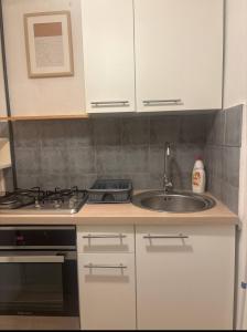 a kitchen with white cabinets and a sink and a stove at Zakątek in Warsaw