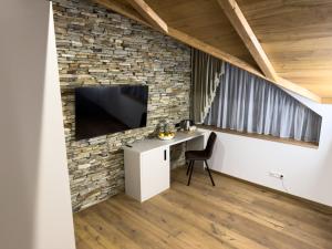 Zimmer mit einem Schreibtisch und einem TV an einer Backsteinwand in der Unterkunft Vila Vento in Veľký Slavkov