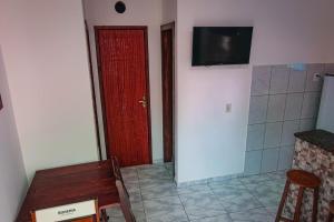 a room with a red door and a tv on the wall at Apartamento da Joana - 2ª Praia, Morro de SP in Morro de São Paulo