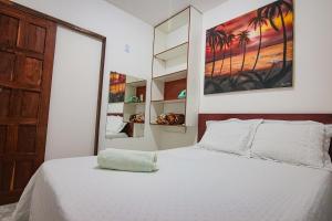 a bedroom with a white bed with a large painting on the wall at Apartamento da Joana - 2ª Praia, Morro de SP in Morro de São Paulo