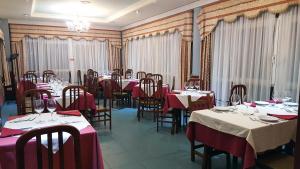 a dining room with tables and chairs with red tablecloths at Hotel Avenida III in Villadangos del Páramo