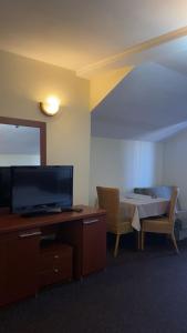 a room with a tv and a desk with a table and a chair at Hotel Restaurant Arena in Kastriot +6 photos