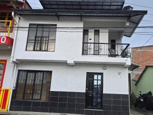 een wit huis met zwarte ramen en een balkon bij Pipe's House in Salento