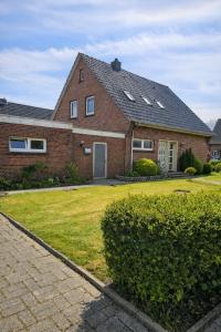 une maison en briques avec une cour d'herbe devant elle dans l'établissement Ferienwohnungen Avenor, à Norden