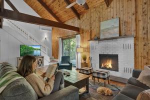 a woman sitting on a couch in a living room with a fireplace at LUX Lakefront, Pool, Hot Tub, Game Room, FIFA 2026 in Bushkill