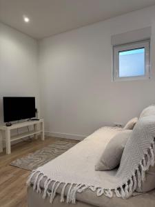 une chambre blanche avec un lit et une télévision dans l'établissement Charming Little House with patio, à Toulouse