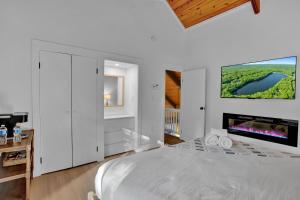 a white bedroom with a large bed and a flat screen tv at LUX Lakefront, Pool, Hot Tub, Game Room, FIFA 2026 in Bushkill