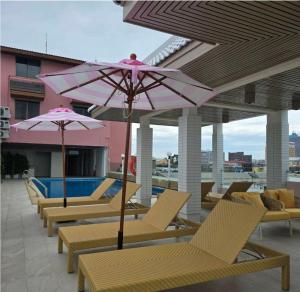 een rij stoelen en parasols op een patio bij Smile Court Pattaya by Mike Group in Pattaya