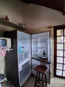 a kitchen with an empty refrigerator with a wooden stool at Chalé 4 Quartos Casa Jasmin in Chã Grande