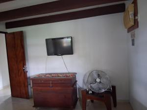 a room with a fan and a tv on a wall at Chalé 4 Quartos Casa Jasmin in Chã Grande