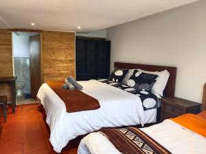 a bedroom with two beds with white sheets at Hospedaje Rural Pistacia Vera - Villa de Leyva in Villa de Leyva