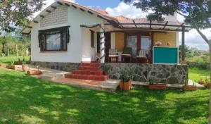 a small white house with a stone wall at Hospedaje Rural Pistacia Vera - Villa de Leyva in Villa de Leyva